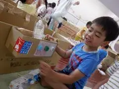 写真:ペットボトルキャップのボタンをつける子