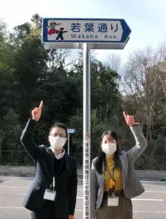 写真:若葉通りの看板とプロジェクトメンバー