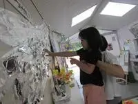 写真:先生に抱えられて高い場所を飾り付けする子
