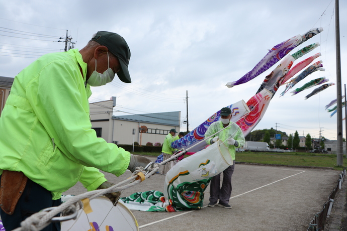 高野まちづくりの会の男性がこいのぼりが絡まないようにこいのぼりの紐を手にしている写真